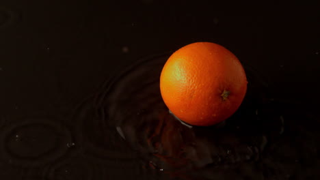 gotas de naranja en una superficie negra y húmeda