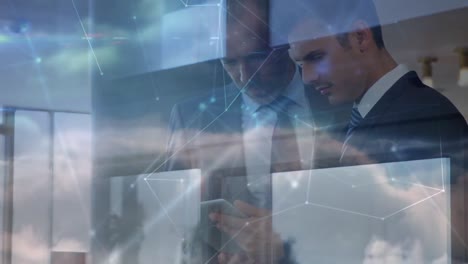 Network-of-connections-over-two-caucasian-businessmen-using-digital-tablet-against-clouds-in-the-sky