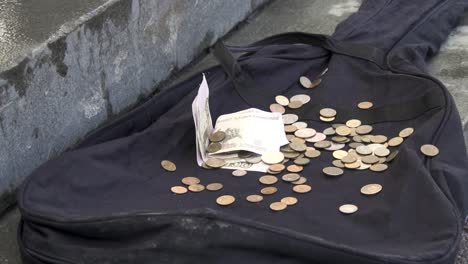 money and coins in guitar case on the street