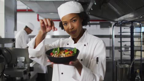 Portrait-of-african-american-female-chef-garnishing-dish-and-looking-at-camera