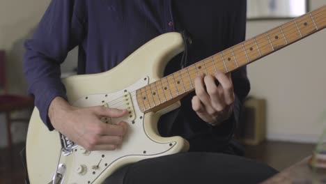 closeup up, musician play a guitar solo with hands at indoor plants studio with vintage decoration, white stratocaster style instrument