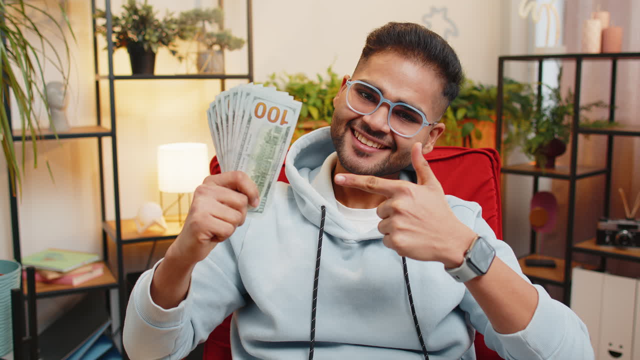 Hombre indio rico, feliz y exitoso contando dinero y celebrando que le ha tocado la lotería, sujetando billetes en dólares