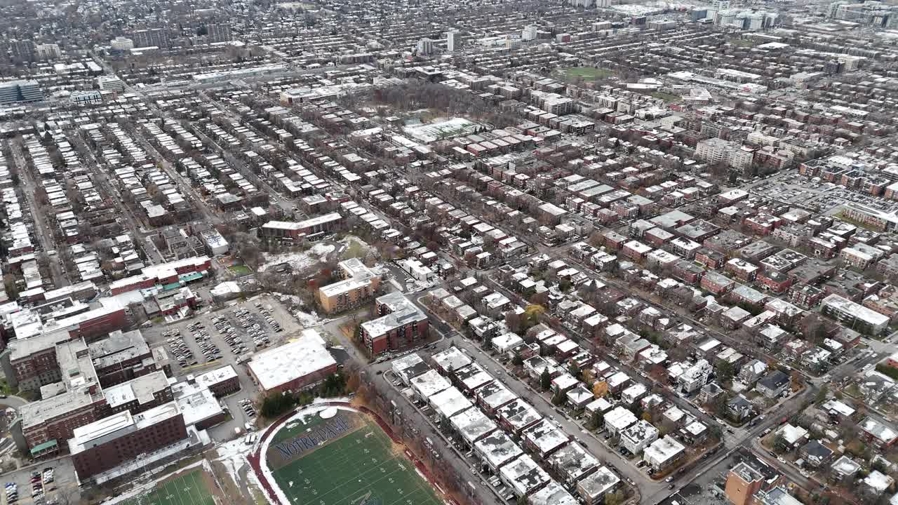 Konut binaları ve yeşil bir futbol sahası olan karlı bir şehrin havadan görünümü, Montreal, Kanada.