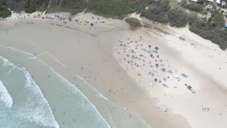 turista en un campamento con olas marinas salpicadas - playa de cilindros, isla de north stradbroke en queensland, australia