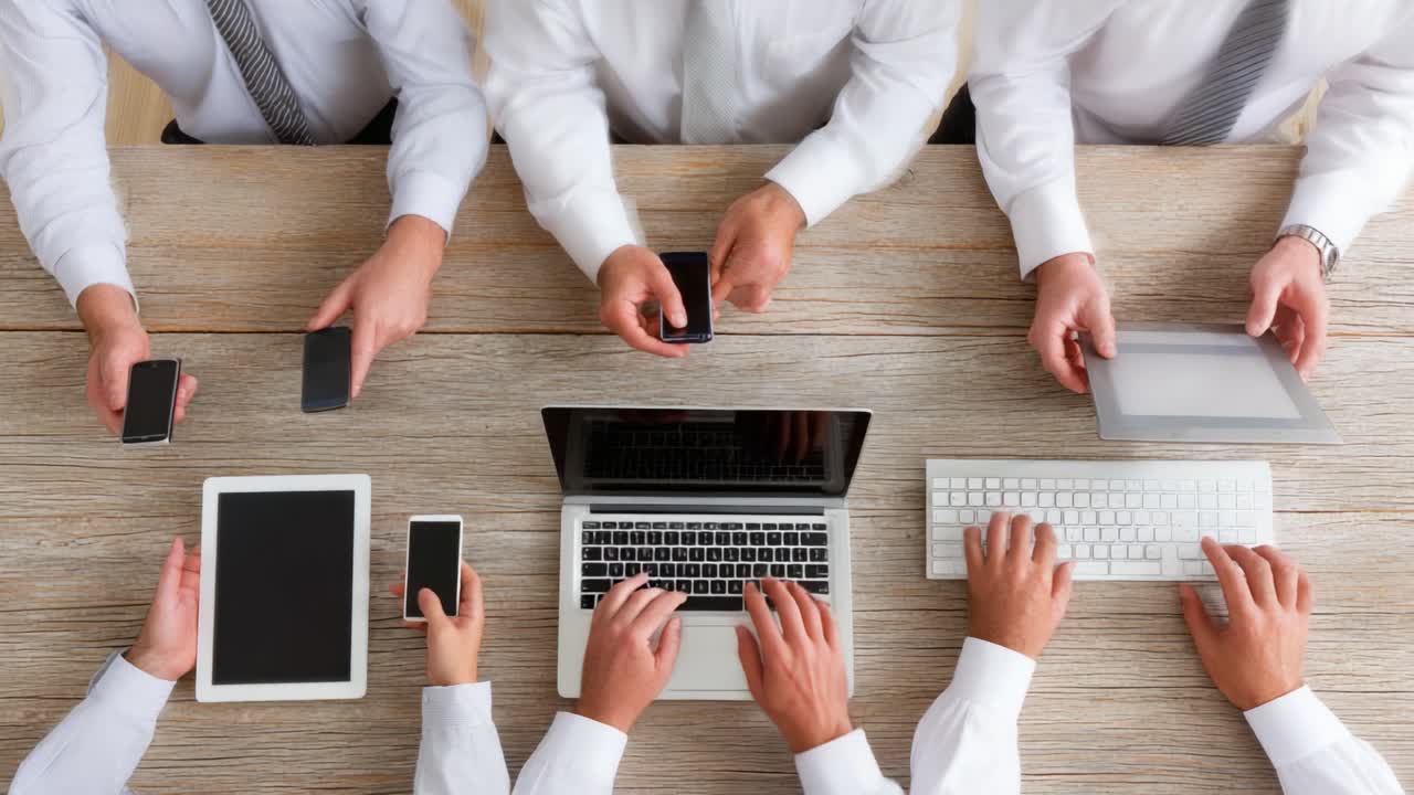 A Collaborative Meeting Featuring Multiple Devices: Smartphones, Tablets, and a Laptop on a Wooden Table, Showcasing Technology in a Professional Setting