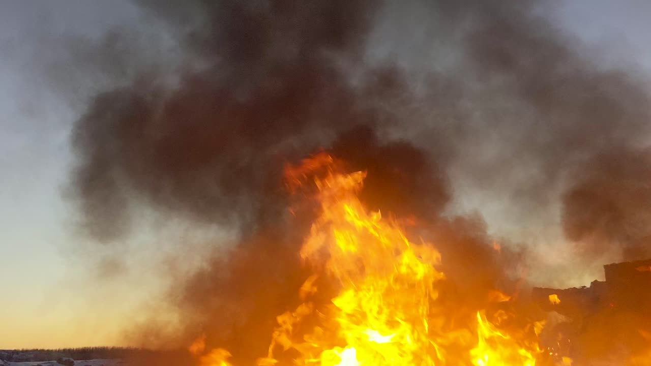 Massive fire burns up oil spill throwing huge black clouds of smoke into the atmosphere as sun rises in the background