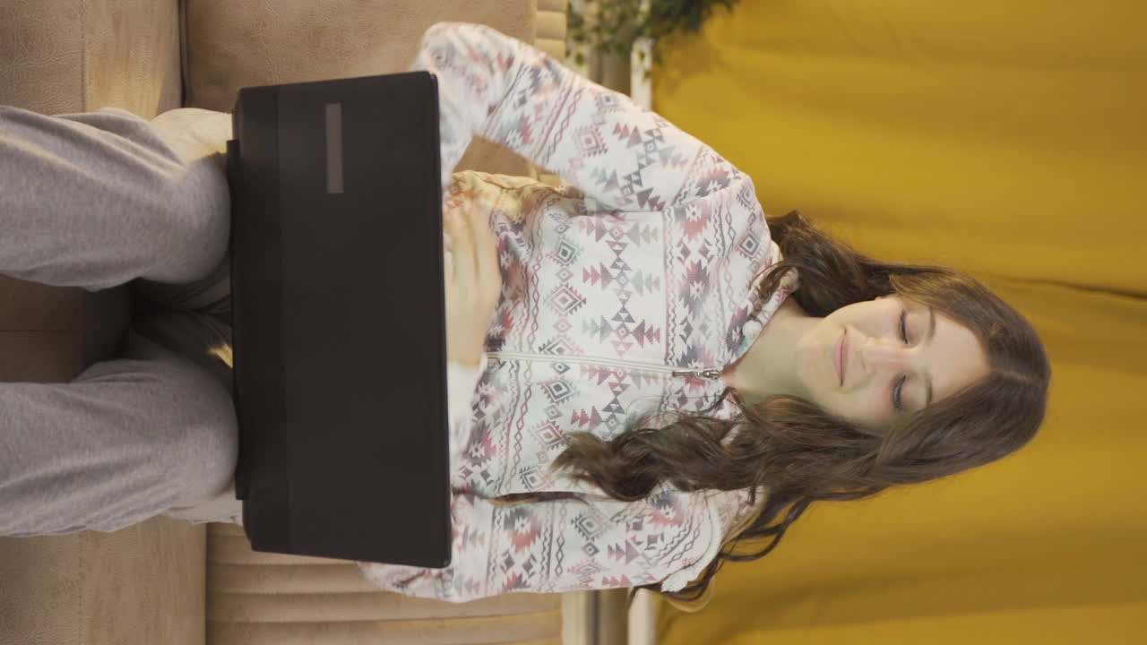 вертикальное видео счастливой молодой женщины, использующей ноутбук ночью.