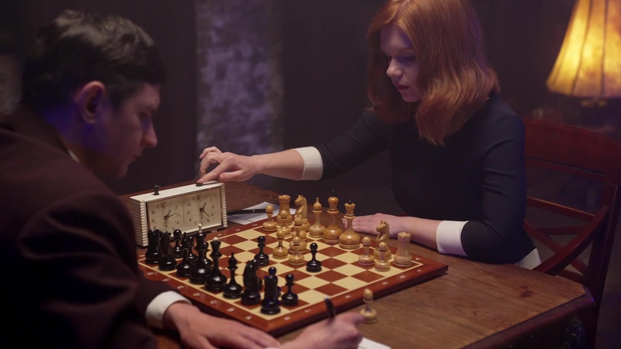 Мужчина и женщина играют в шахматы, записывают ходы и используют часы
