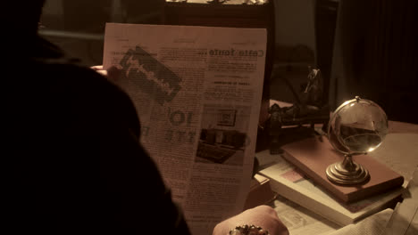 vintage man reading newspaper at a desk