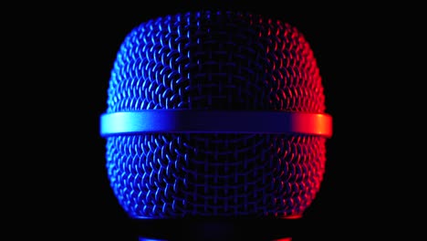 el micrófono gira con la luz de fondo azul y roja. la cuadrícula dinámica del microfono gira de cerca
