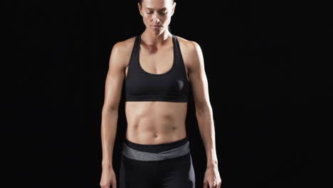 Fit-young-Caucasian-woman-athlete-stands-confidently-in-sportswear-on-a-black-background