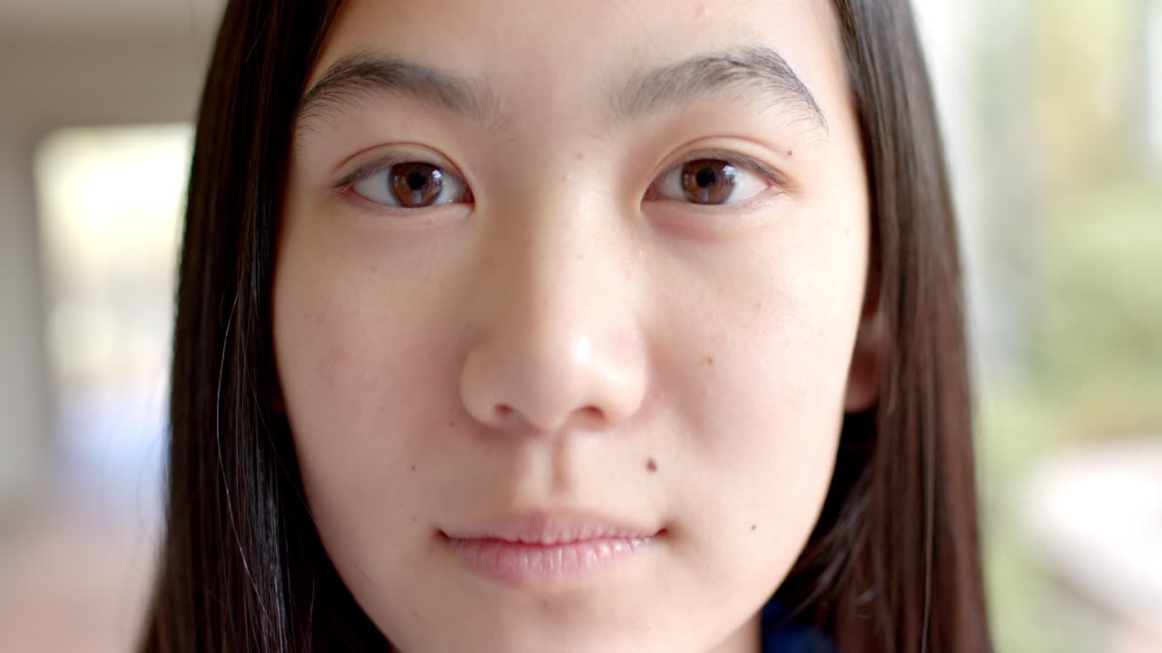 Close-up of a teenage Asian girl with long dark hair and a subtle smile