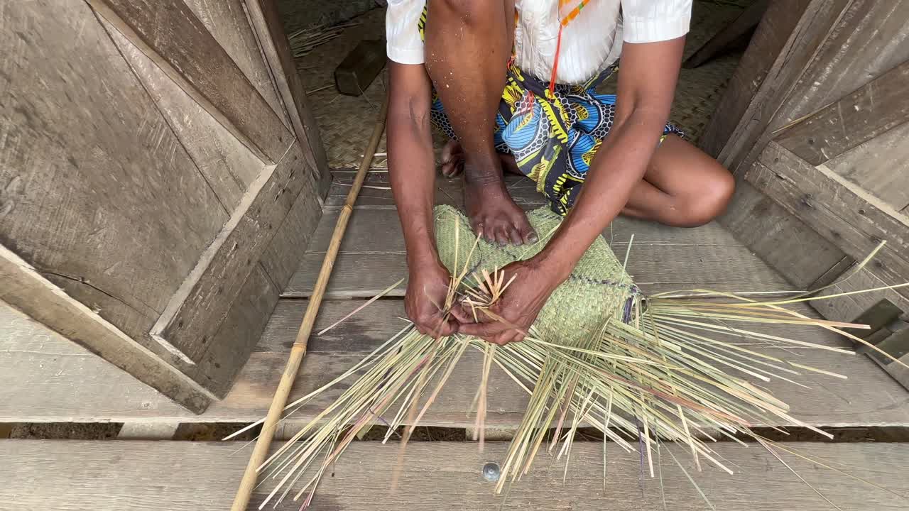 Donna malgascia che tesse un cesto utilizzando il metodo tradizionale ad Ambinanitelo, Madagascar.