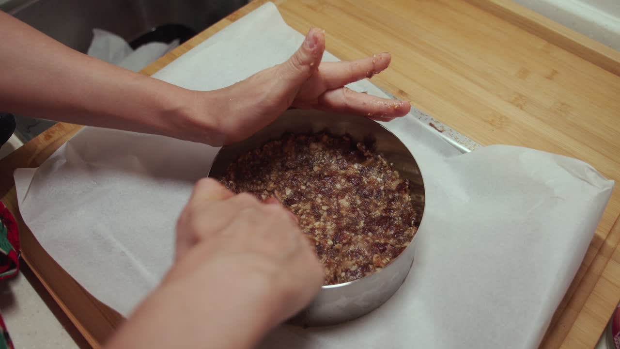 Una donna mette un composto vegetariano di frutta e noci in una teglia circolare.