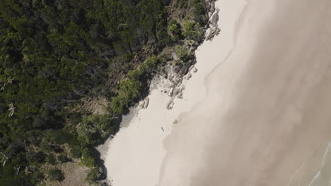 Un-Dron-De-4k-Se-Aleja-Lentamente-De-Dos-Personas-Tendidas-En-Una-Playa-De-Una-Isla-Desierta-En-Australia