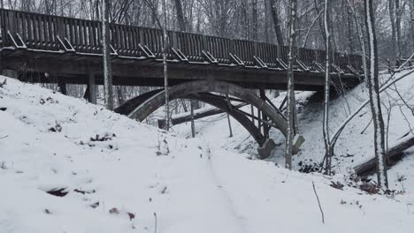 close up of a large peaceful arch wooden bridge in the snow over a frozen creek river in the winter during the snow