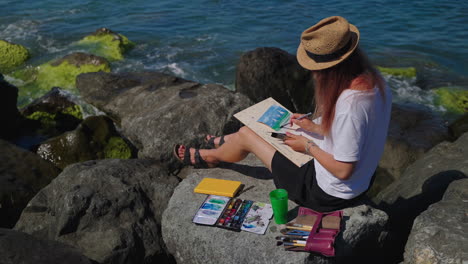 woman painting seascape on the beach