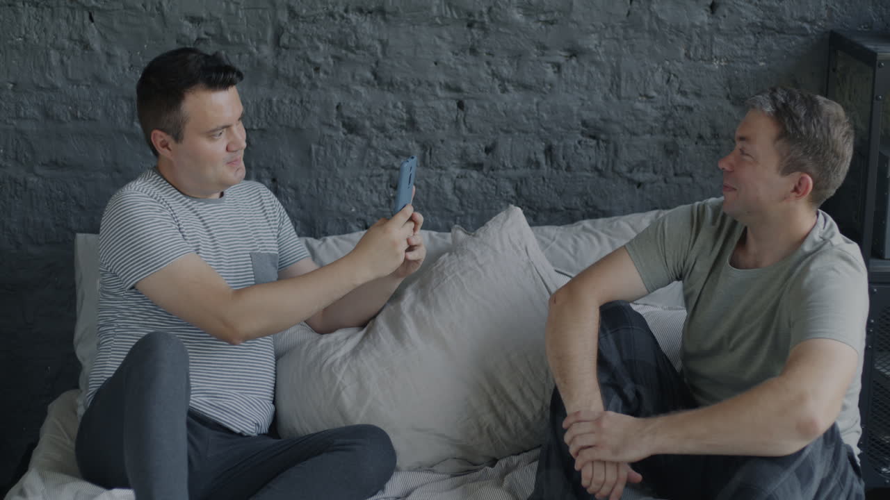 Two men taking a selfie in bed