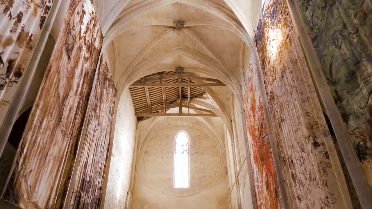 Slow motion shot of of large archways and paintings within a French Abbey
