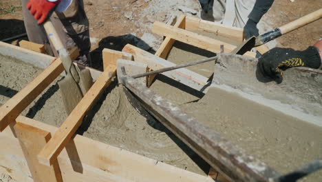 work with concrete at the construction site workers take concrete into a wooden mold heavy manual la