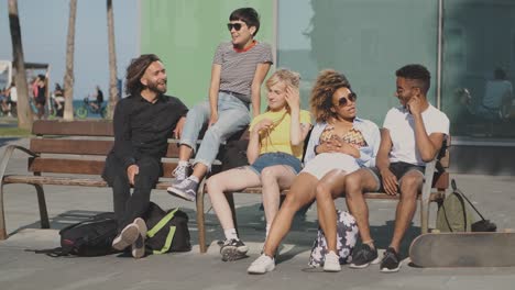 lounging diverse friends on bench in sunshine