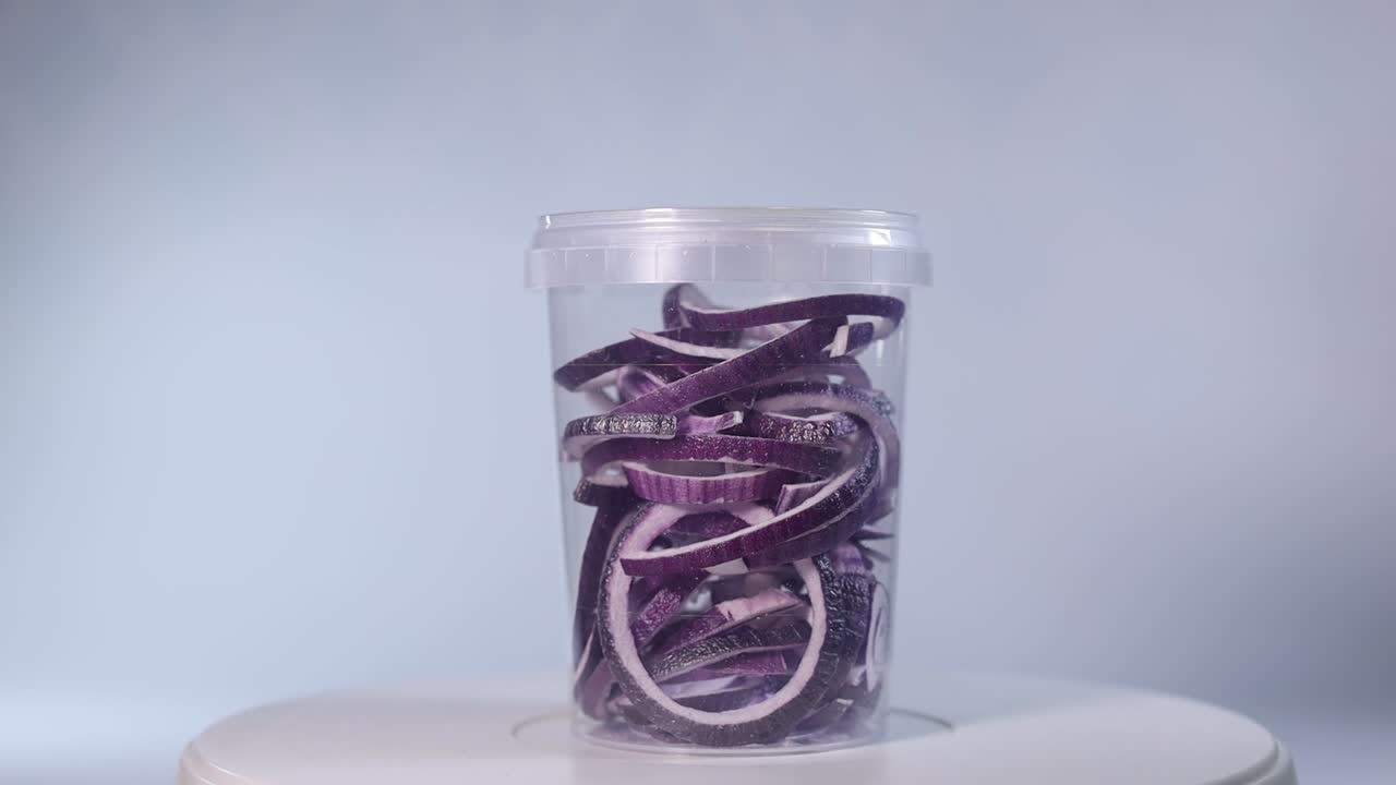 A clear jar filled with freeze-dried onion rings, showcasing their vibrant purple and white hues. Perfect for cooking, garnishing, or long-term storage.