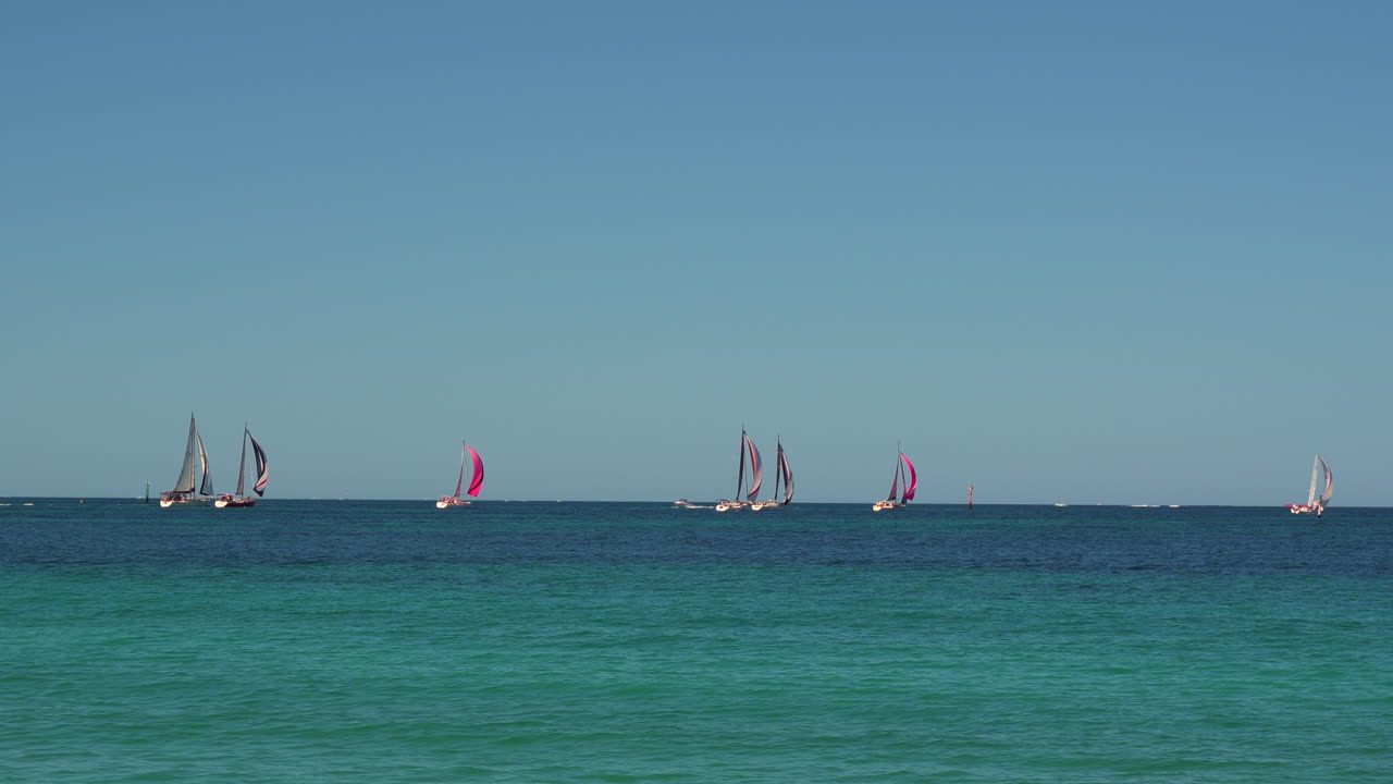 Sailing yachts with vibrant sails, gliding across the vast open sea under clear blue skies. The calm waters of the Indian Ocean off Perth Australia