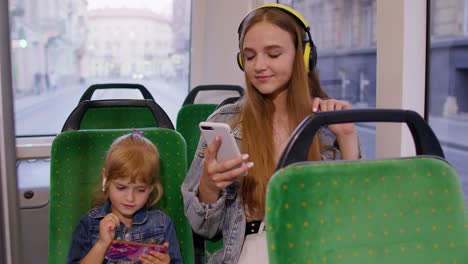 Child-girl-with-mother-using-smartphone-with-headphones,-earphones-listening-music,-funny-dancing