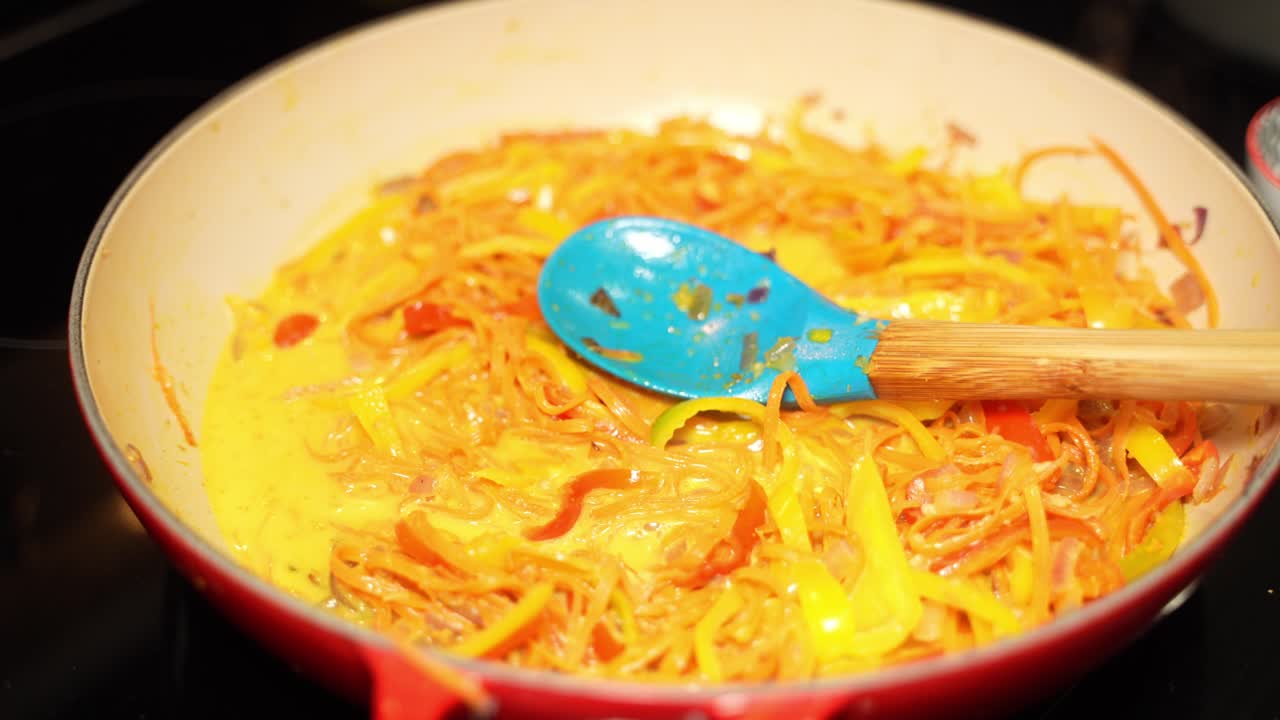 Slices of orange capsicum getting cooked on frying pan by chef.