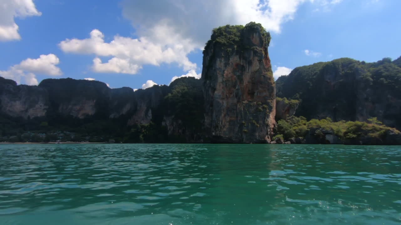 Slow motion 120 fps panning shot of beautiful cliffs of Railay Thailand from moving boat in turquoise waters