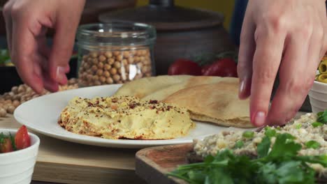 israeli cuisine. putting plate with hummus decorated with pita close-up. national food, middle eastern culture. vegan chickpea puree snack. appetizer made from mashed chickpeas