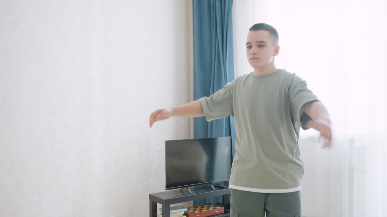 Teen boy performs warmup routine while standing on bright green fitness mat in cozy living room filled with daylight, focused expression shows dedication to staying active and healthy indoors
