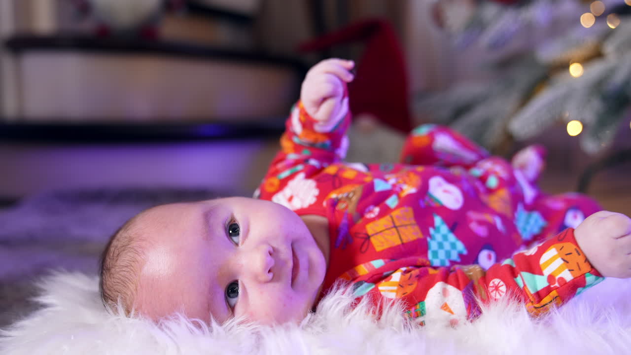 Cheerful smiling baby lies on his back tossing his arms and legs. Adorable healthy little child close up. Blurred backdrop.