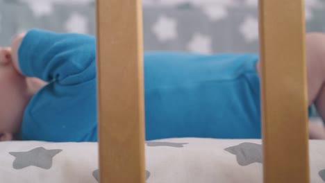 niño pequeño con las piernas desnudas lame la mano descansando en una cuna moderna