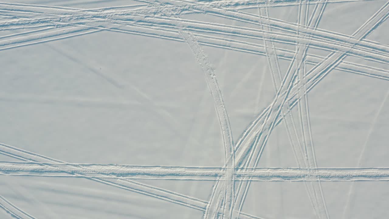 Top down aerial of snowmobile, snow machine tracks in fresh winter snow cover in arctic