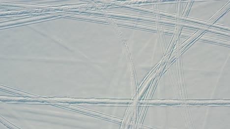 antena de arriba hacia abajo de motos de nieve, pistas de máquinas de nieve en la cubierta de nieve fresca del invierno en el ártico