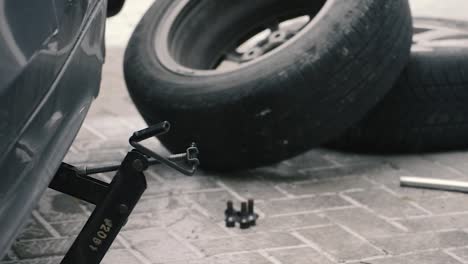 a workspace of a mechanic during tire change and winter car prep on the backyard snow-covered pavement, camera panning from left to right