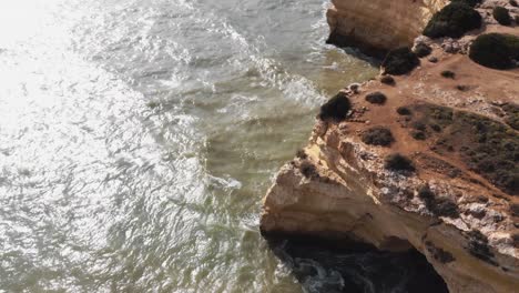 Marinha-beach-cliffs-in-Benagil-mediterranean-village-in-Algarve,-Portugal---Fly-over-tilt-up-Reveal-Aerial-shot