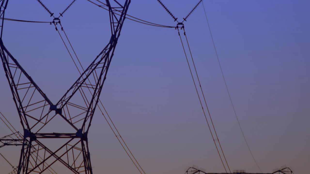 Camera shifting reveals lattice tower plus Y pylons while HUD updating readouts to monitor grid