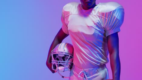 Video-of-portrait-of-african-american-american-football-player-over-blue-to-pink-neon-background