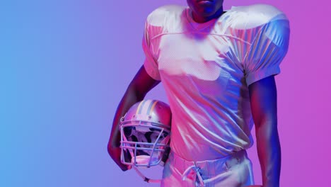 video of portrait of african american american football player over blue to pink neon background