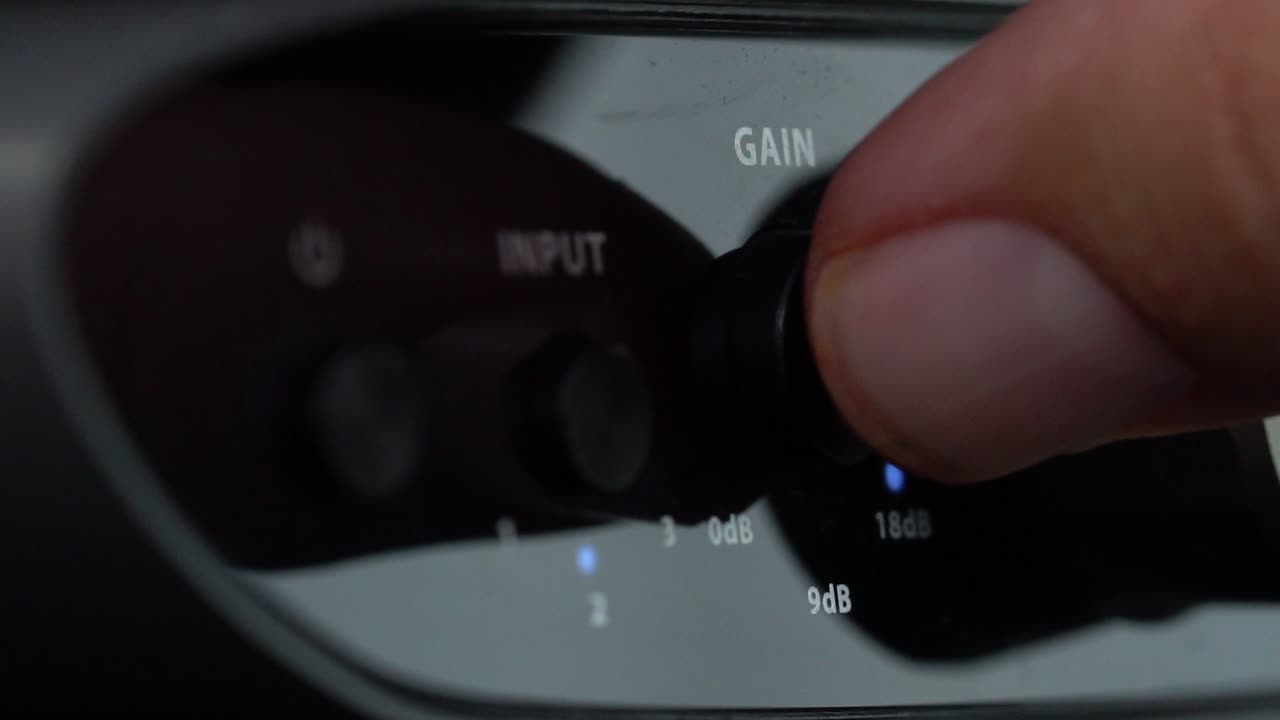One finger adjusting the input gain knob on an audio interface