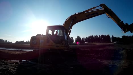 yellow excavator moves through the mud and sludge with a help of bucket