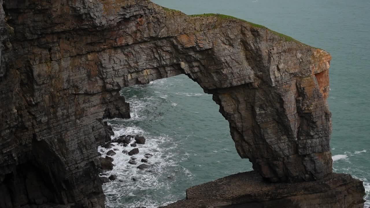 formación rocosa de arco conocida como puente verde de gales en la costa galesa