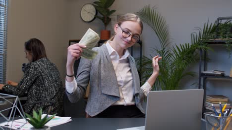 excited businesswoman holding cash in an office