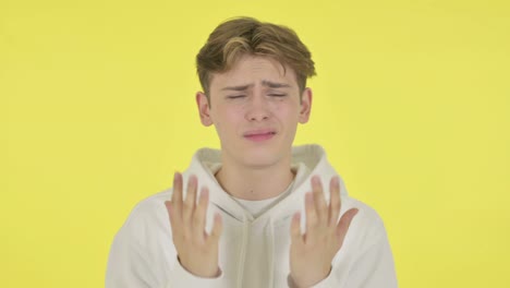 disappointed young man reacting loss on yellow background