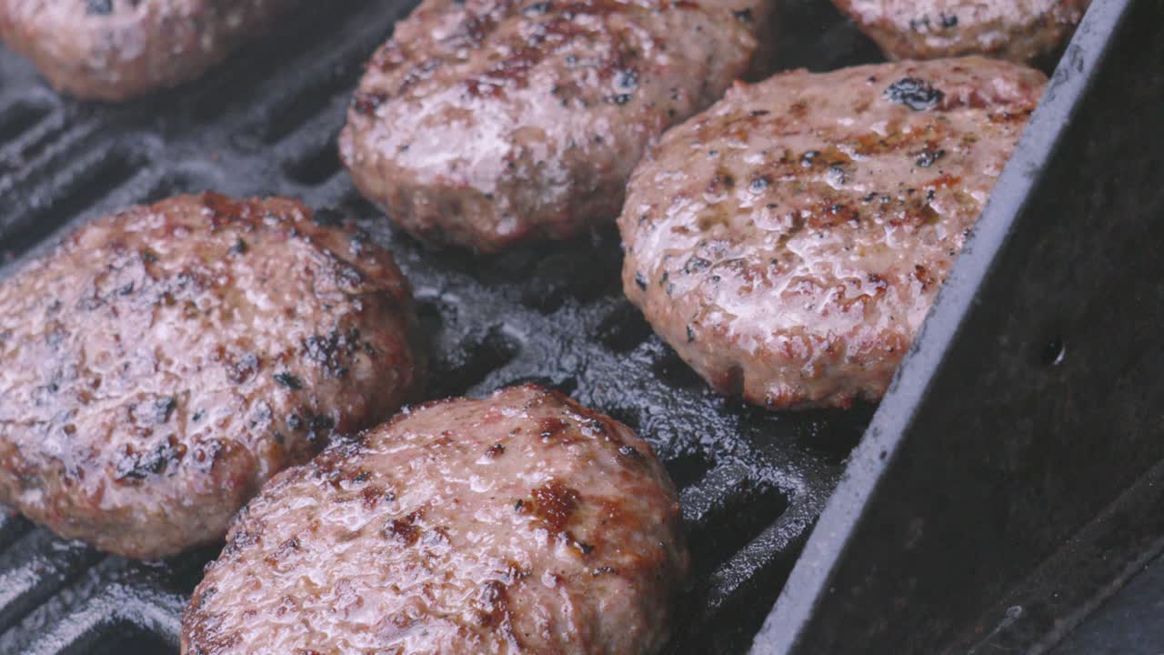 Group of Beef Burgers Gently Cooking on Hot Iron Grill on BBQ Cooked Outside in Natural Lighting. Delicious Juicy Meat Grilled.