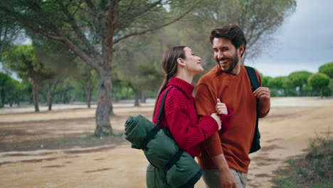 happy couple hiking forest with backpacks vertical. tourists laughing enjoy walk