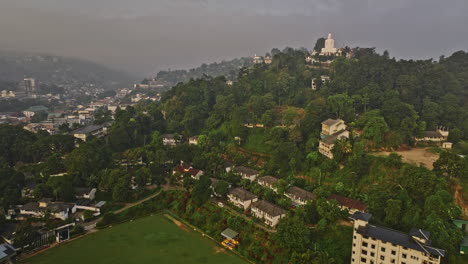 Kandy,-Sri-Lanka:-Luftaufnahme-Eines-Cricketplatzes-Und-Eines-Buddhistischen-Tempels-Mit-Einer-V29-Drohne-Aus-Dem-Flugzeug-über-Einem-Hügel,-Die-Einen-Wunderschönen-Blick-Auf-Die-Stadtlandschaft-Bei-Sonnenaufgang-Mit-Dichten-Nebelwolken-Bietet-–-Aufgenommen-Mit-Mavic-3-Cine-–-April-2023