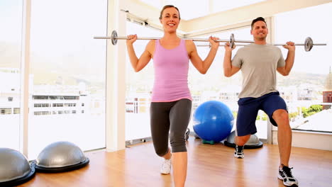 Fit-couple-doing-lunges-with-barbells